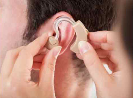 woman fitting hearing aide into mans ears