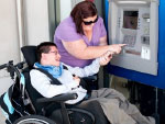 carer using a person in wheelchair with intellectual disability finger to type PIN number on AMT keypad 